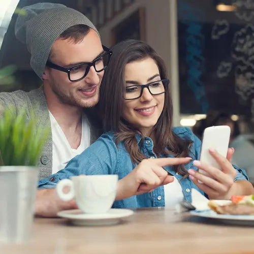 Das_Jahr_2024_mit_Bild_eines_jungen_paerchens_aus_mann_und_frau_sitzend_an_einem_tisch_und_laechelnden_gesichtern_auf_ein_smartphone_schauend