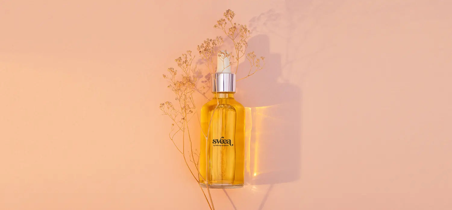 Glasflasche_mit_Pipette_und_einem_orangen_Elexier_auf_rosa_Hintergrund